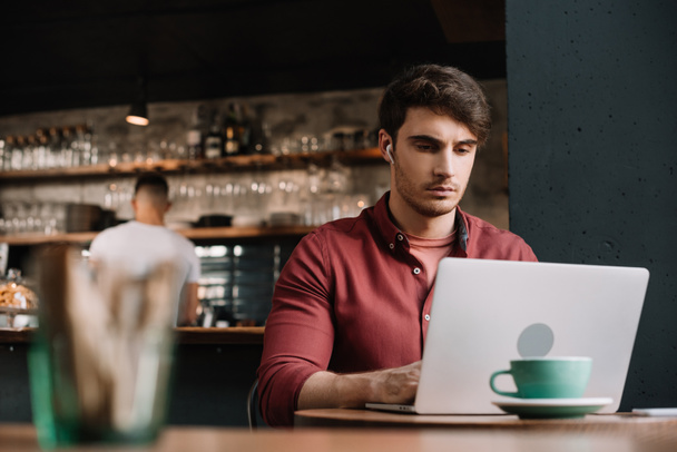 valikoiva painopiste freelancer langattomissa kuulokkeissa kannettavan tietokoneen avulla kahvilassa
 - Valokuva, kuva