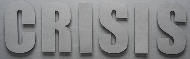 vista superior de la palabra crisis sobre fondo gris con sombras, plano panorámico
 - Foto, Imagen