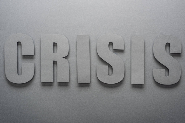 top view of paper cut word crisis on grey background with shadows - Φωτογραφία, εικόνα