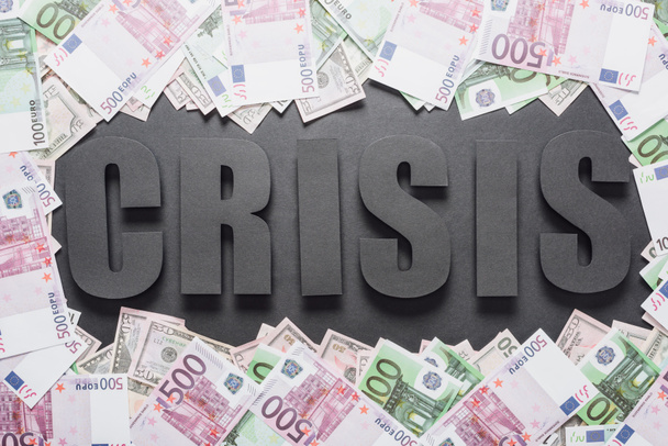 top view of word crisis in frame of dollar and euro banknotes on black background with shadows - Photo, Image