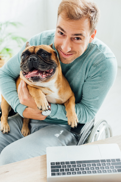 Disabled man holding french bulldog and smiling at camera - Fotografie, Obrázek