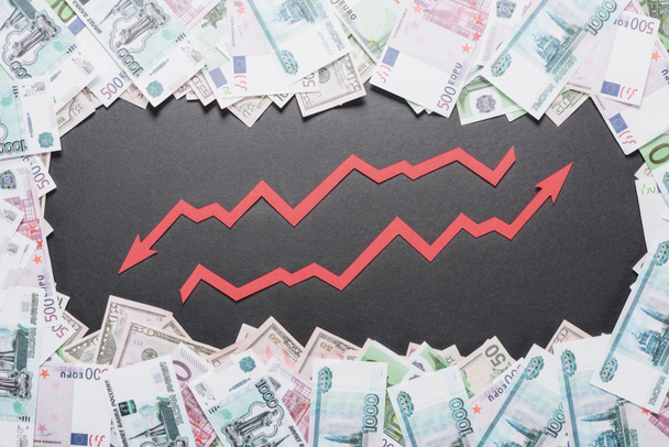 Pfeile für Wachstum und Rezession im Rahmen von Dollar-, Euro- und Rubel-Banknoten auf schwarzem Hintergrund - Foto, Bild