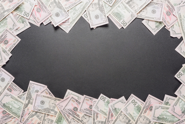 frame van verstrooide dollarbankbiljetten op zwarte achtergrond met kopieerruimte - Foto, afbeelding