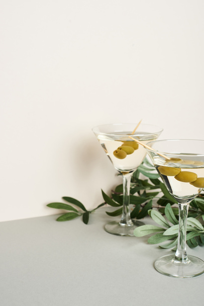 Classic martini cocktails with olive branch on grey surface - Fotoğraf, Görsel