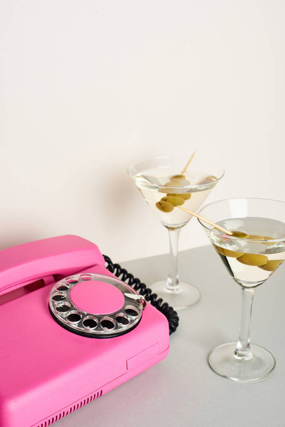 Różowy telefon retro z koktajlami martini na białym tle - Zdjęcie, obraz