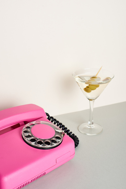 Ročník růžový telefon se sklenkou koktejlu na bílém pozadí - Fotografie, Obrázek