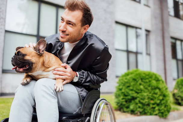 Mosolygó fogyatékos férfi simogatás francia bulldog a városi utcán - Fotó, kép