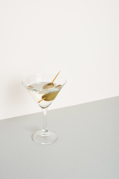 Glass of vermouth with olives on grey surface isolated on white background - Foto, afbeelding