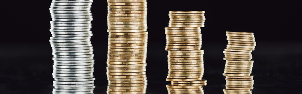 panoramic shot of stacked silver and golden coins on surface with reflection isolated on black - Foto, Bild