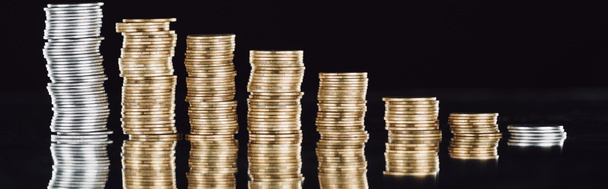 панорамный снимок сложенных серебряных и золотых монет на поверхности с отражением, изолированным на черном
 - Фото, изображение