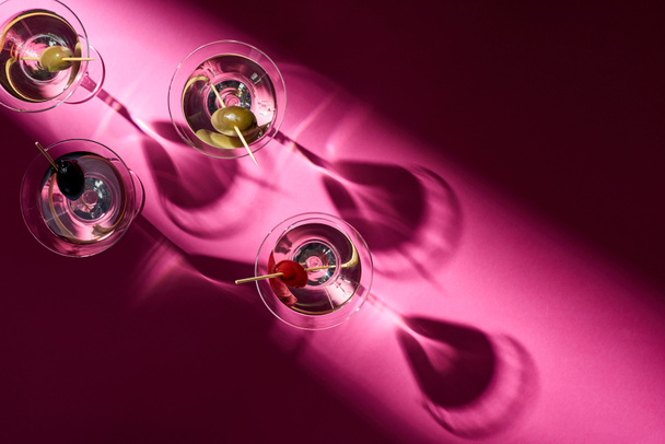 Вид сверху на коктейли мартини с оливками на розовом фоне
 - Фото, изображение