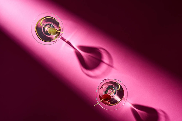 Bovenaanzicht van twee cocktails met schaduwen op roze achtergrond - Foto, afbeelding