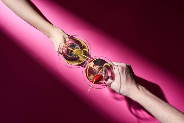 Cropped view of man and woman holding cocktails on pink background with shadow - Foto, Imagem