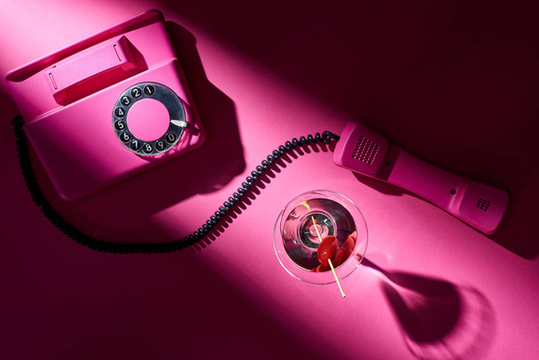 Κάτοψη της vintage τηλέφωνο και κοκτέιλ με σκιά σε ροζ φόντο - Φωτογραφία, εικόνα