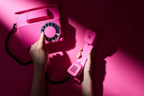 Cropped view of woman using retro telephone on pink background - Photo, image