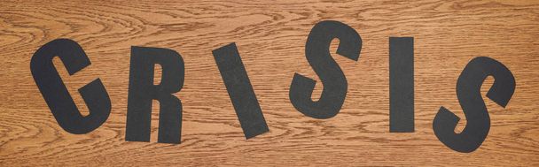 vista superior de la crisis palabra de corte de papel negro en la superficie de madera, plano panorámico
  - Foto, imagen