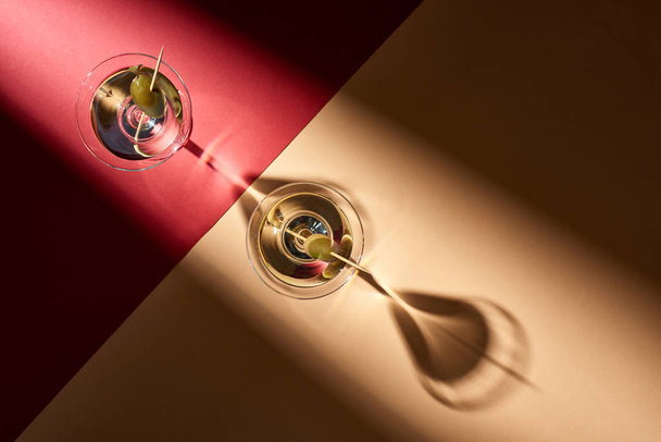 Top view of martini with olives on red and beige background - 写真・画像