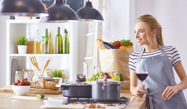 Bella donna in cucina sta bevendo vino rosso
 - Foto, immagini