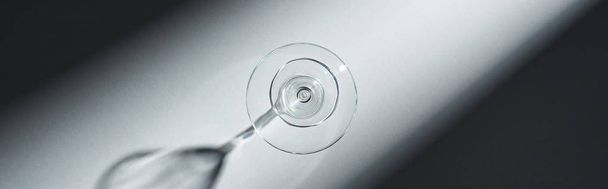 Top view of empty glass for martini with shadow on grey background, panoramic shot - Photo, image