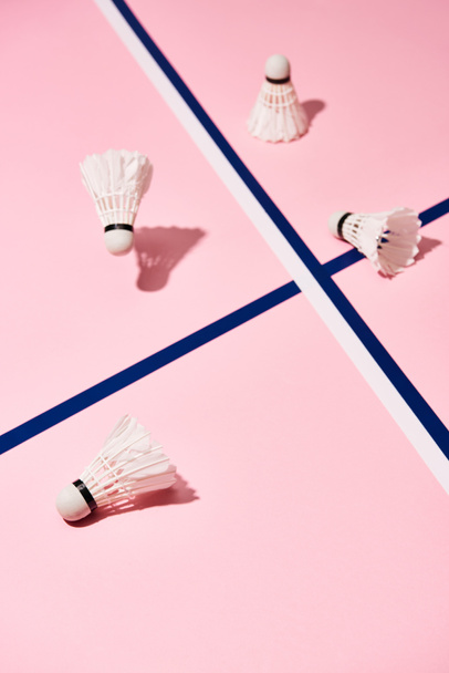 Badminton shuttlecocks with shadow on pink surface with blue lines  - Фото, зображення