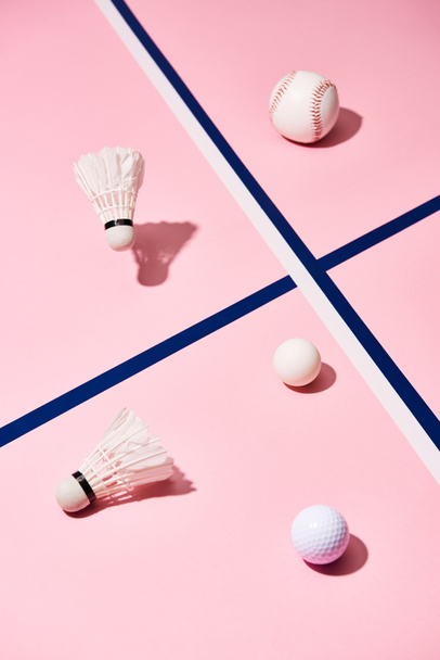 Badminton shuttlecocks with tennis, baseball and golf balls on pink surface - Foto, afbeelding