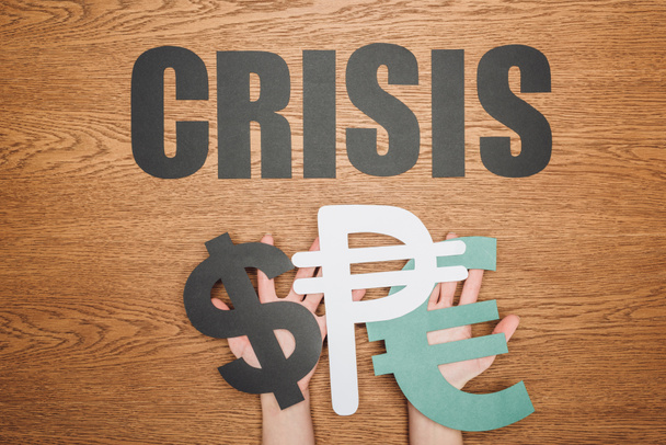 kivágott kilátás nő gazdaság dollár, peso és europapír vágott szimbólumok, és a szó krízis fa íróasztal - Fotó, kép