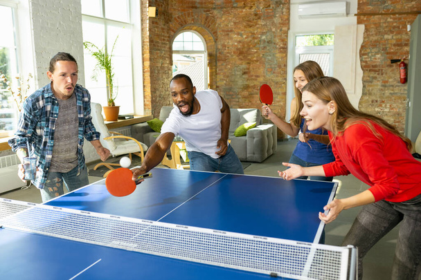 Young people playing table tennis in workplace, having fun - Foto, imagen