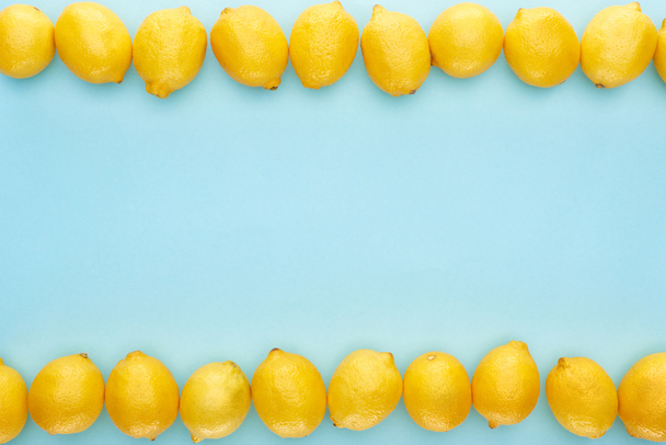 flache Lage mit reifen gelben Zitronen in Linien auf blauem Hintergrund - Foto, Bild