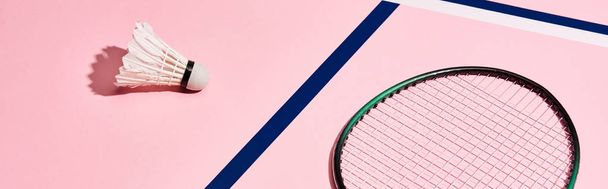 Badminton racket and shuttlecock on pink background with blue lines, panoramic shot - Fotó, kép