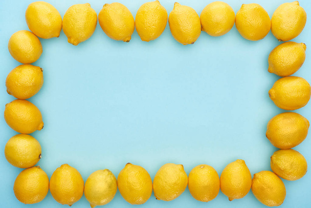 quadratischer Rahmen aus reifen gelben Zitronen auf blauem Hintergrund mit Kopierraum - Foto, Bild