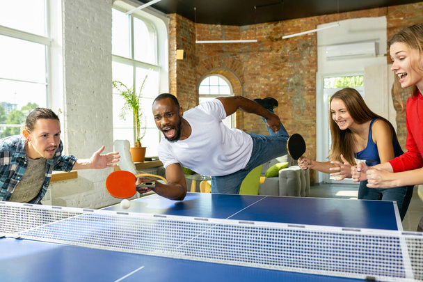 Young people playing table tennis in workplace, having fun - Valokuva, kuva