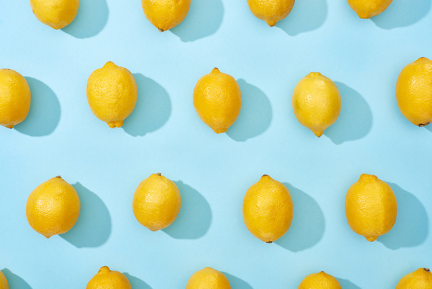 patrón de limones amarillos maduros sobre fondo azul con sombras
 - Foto, Imagen