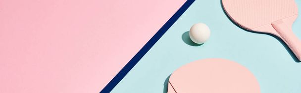 Raquetes de pingue-pongue e bola na superfície pastel com linha azul, tiro panorâmico
 - Foto, Imagem
