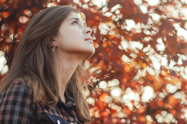 profile of a beautiful young woman looking up gratefully, girl walking through autumn nature in a park - Photo, image