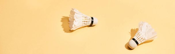 Two badminton shuttlecocks with shadow on yellow surface, panoramic shot - Photo, Image