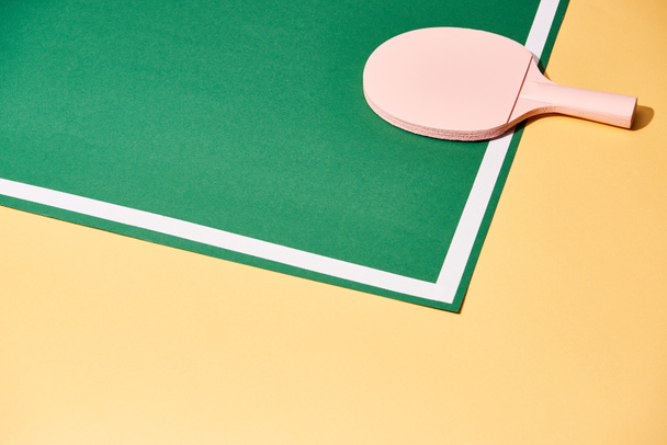 Raquette en bois pour tennis de table sur fond vert et jaune
 - Photo, image