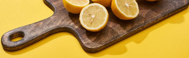 ripe cut lemons on wooden cutting board on yellow background, panoramic shot - Photo, Image
