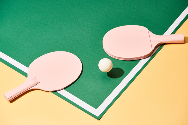 Raquettes et balles en bois pour tennis de table sur surface verte et jaune
  - Photo, image