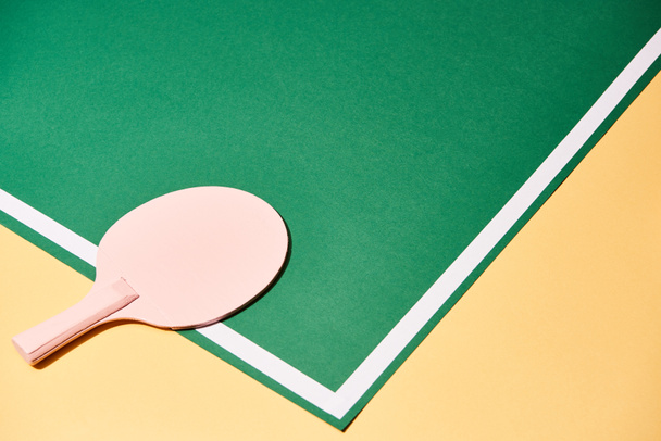 Table tennis racket on playing table on yellow surface - Фото, зображення