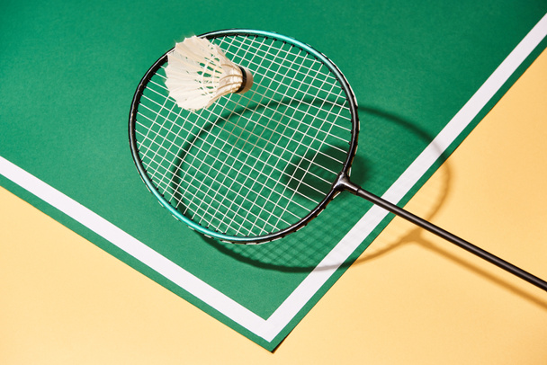 Raqueta de bádminton y lanzadera en superficie verde y amarilla con línea
 - Foto, Imagen