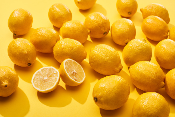 ripe cut and whole lemons on yellow background - Foto, afbeelding