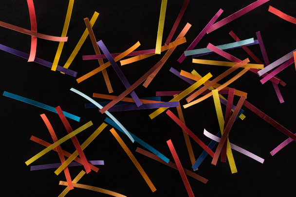 top view of multicolored abstract lines scattered isolated on black background, connection and communication concept - 写真・画像