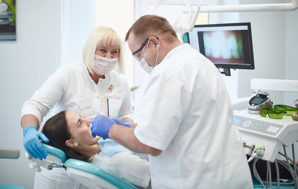 Lääkäri hammaslääkäri kohtelee hampaita kaunis nuori tyttö potilas. Tyttö hammaslääkärin vastaanotossa. Lääkäri hammaslääkäri kohtelee hammas - Valokuva, kuva