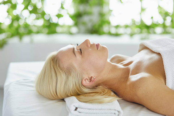 Mulher bonita com olhos fechados recebendo uma massagem no salão de spa
 - Foto, Imagem