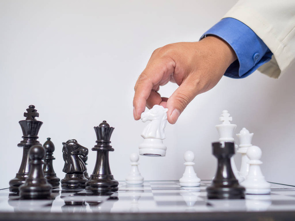 Liikemies käsi liikkuvat kuningas shakki pala aluksella valkoisella taustalla, haasteita suunnittelu liiketoimintastrategian menestykseen käsite
 - Valokuva, kuva