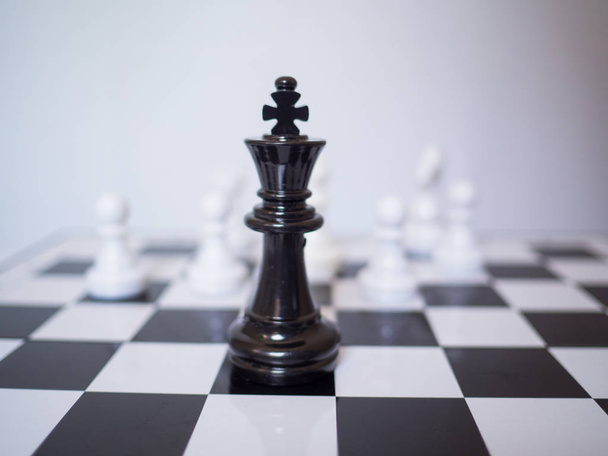 Černý šachový král stojí před bílým šachovým nepřítelem na palubě, výzvy plánování obchodní strategie k úspěchu koncept - Fotografie, Obrázek