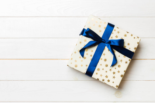 Όμορφο κουτί δώρου με χρωματιστό φιόγκο στο λευκό ξύλινο τραπέζι. Πάνω προβολή banner με χώρο αντιγραφής για το σχεδιασμό σας - Φωτογραφία, εικόνα