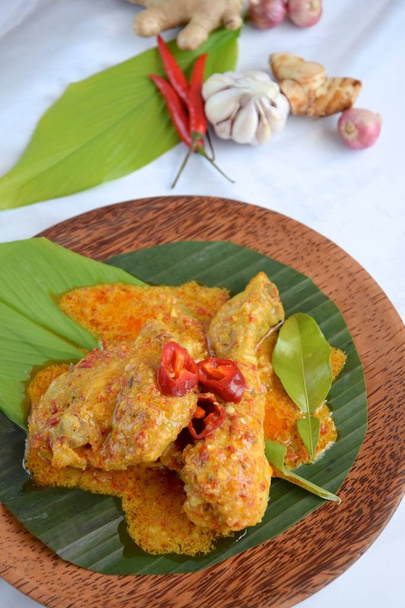 Ayam Kalio Padang o pollo salado mojado rendang. Servido sobre hoja de plátano y hoja de cúrcuma adornar con chile y hoja de lima kaffir - Foto, imagen
