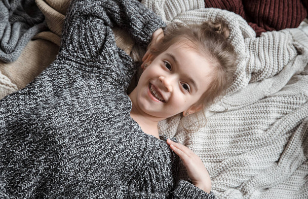 Cute little fun girl in a knitted sweater. - Фото, изображение
