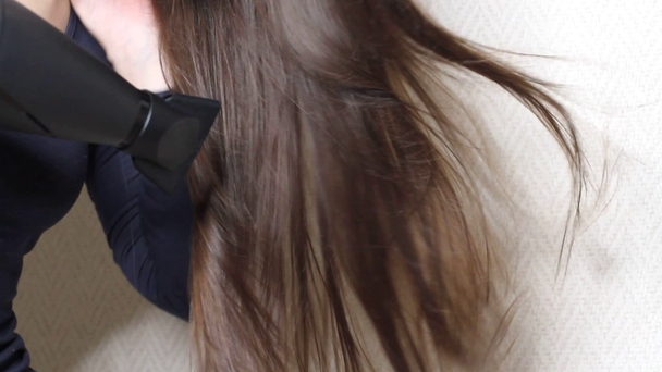 Siyah saç kurutma makinesiyle saç kurutan kadının videosunu kapat. - Video, Çekim